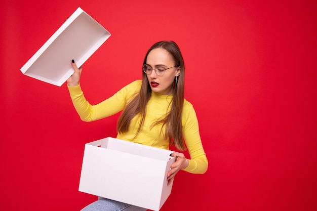 Young woman with white moving box on red background