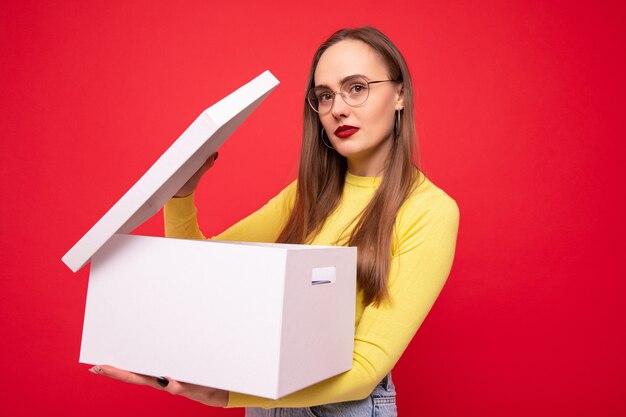 Young woman with white moving box on red background