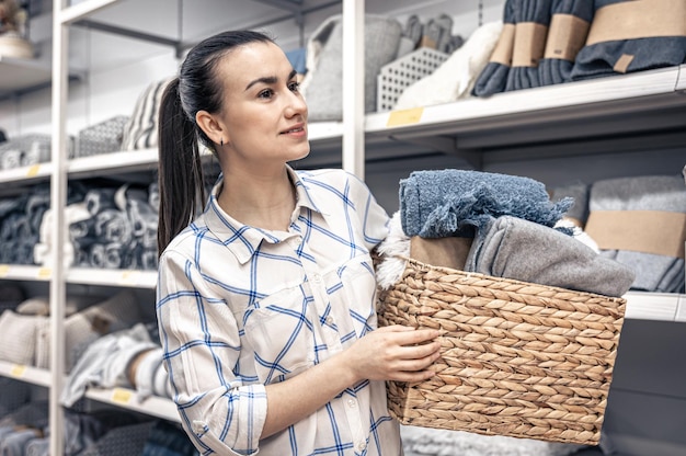 A young woman with a wicker basket full of blankets in a home improvement store