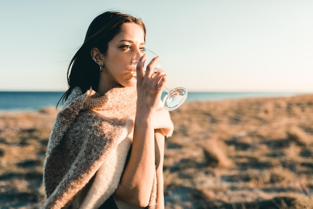 young woman with a wine glass in a field at sunset