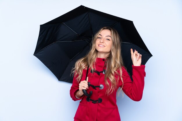 Young woman with winter coat and  holding an umbrella and pointing it