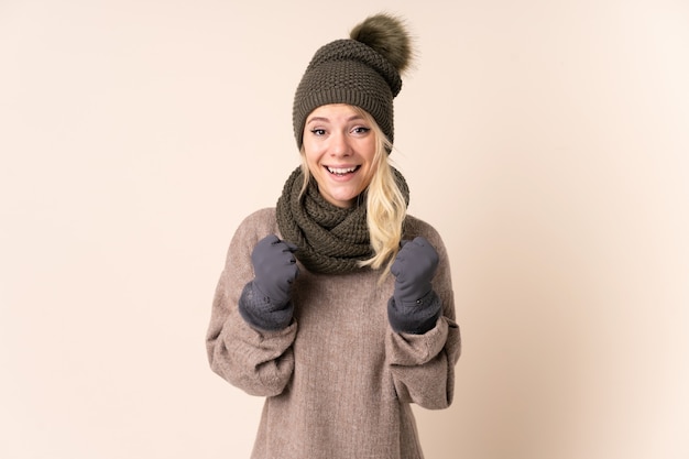 Young woman with winter hat over isolated  celebrating a victory