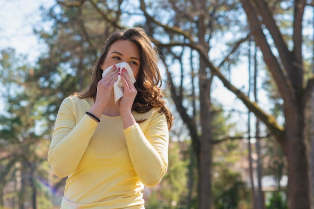 Young woman with with allergy symptom blowing nose