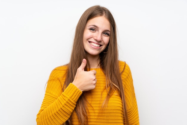 Young woman with yellow over isolated white wall giving a thumbs up gesture