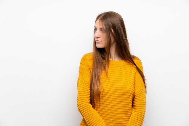 Young woman with yellow over isolated white wall standing and looking side