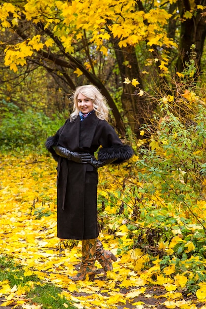 Young woman with yellow leaves walking outside in autumn park