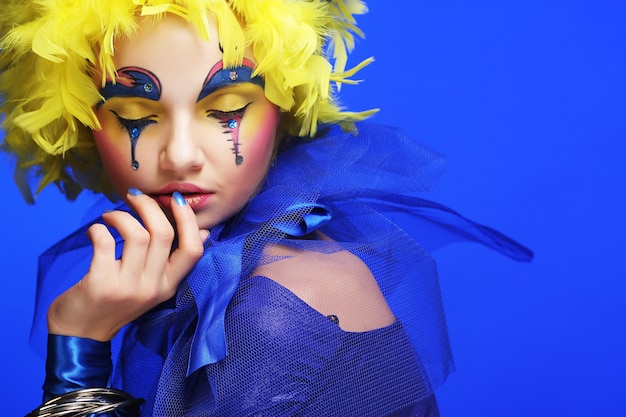 Young woman with yellow wig feather. Holiday theme.