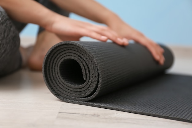 Young woman with yoga mat indoors, closeup