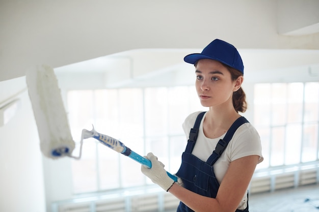 young woman worker painting walls