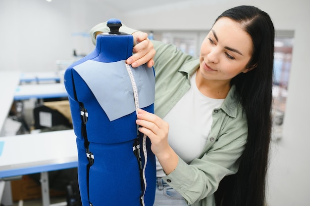 Young woman working as seamstress in clothing factory