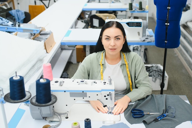 Young woman working as seamstress in clothing factory