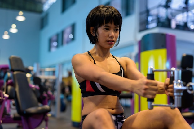 Young woman working back with seated cable row