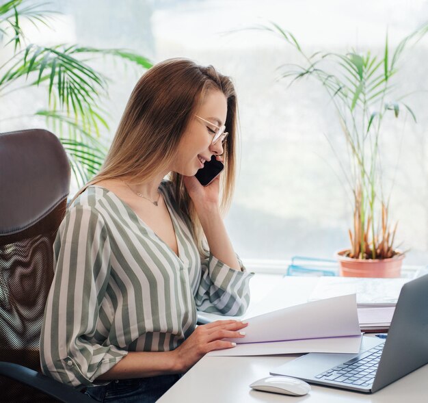 彼女のオフィスでコンピューターに取り組んでいる若い女性