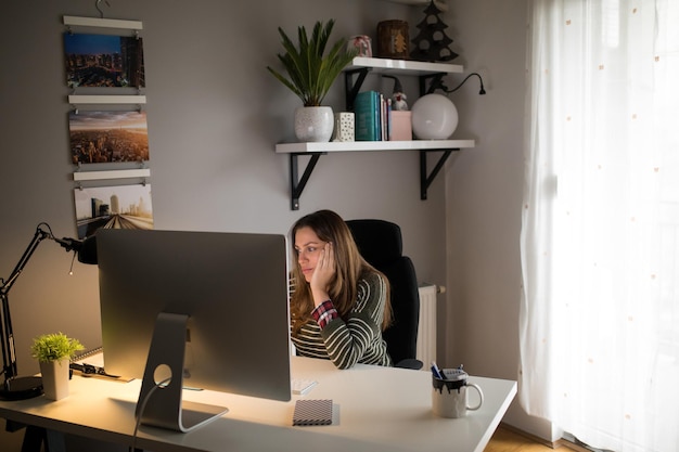 Молодая женщина, работающая на компьютере дома