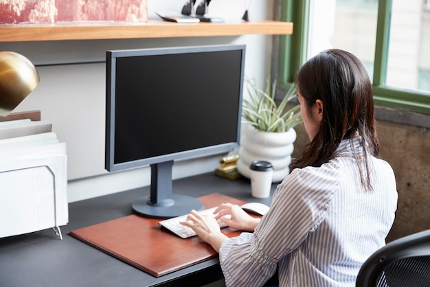 Молодая женщина, работающая за компьютером в офисе крупным планом