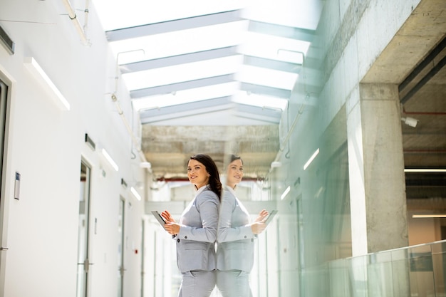 Young woman working on digital tablet in the office hallway