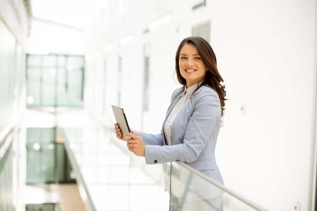 Young woman working on digital tablet in the office hallway