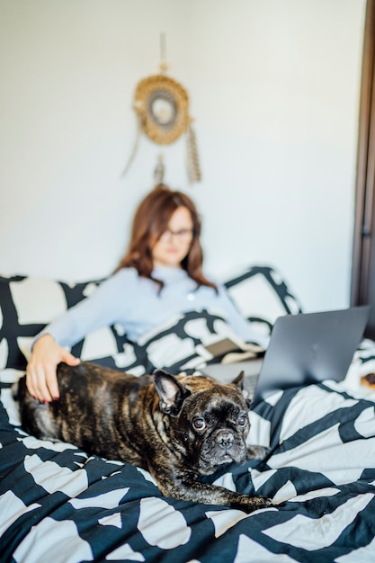 Young woman working from bed at home with computer.