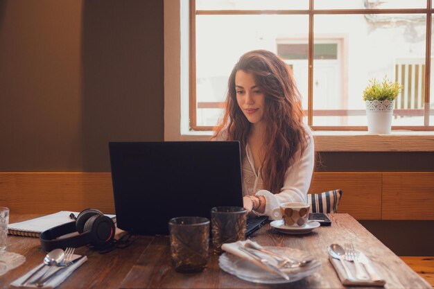 Young woman working from a restaurant with her laptop