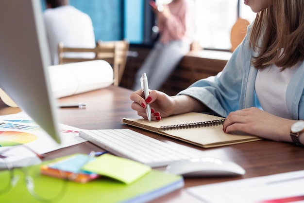 Giovane donna che lavora alla sua scrivania prendendo appunti concentrarsi sulla scrittura a mano su un blocco note