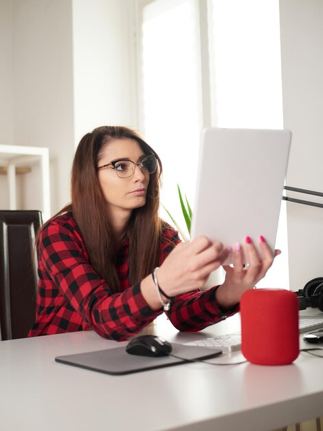 デスクトップPCとデジタルタブレットで自宅で働く若い女性