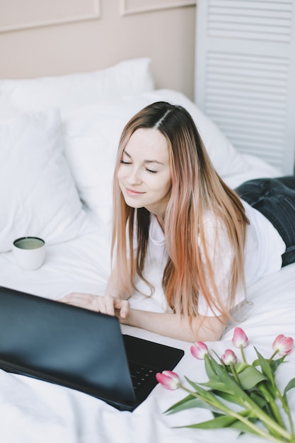 Young woman working on laptop in bed