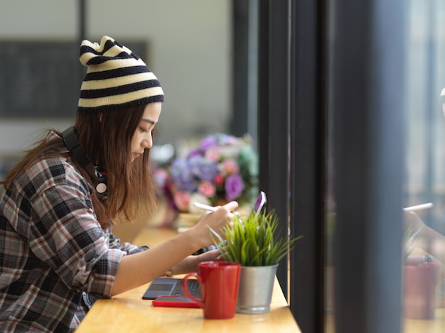 机の上のラップトップに取り組んでいる若い女性