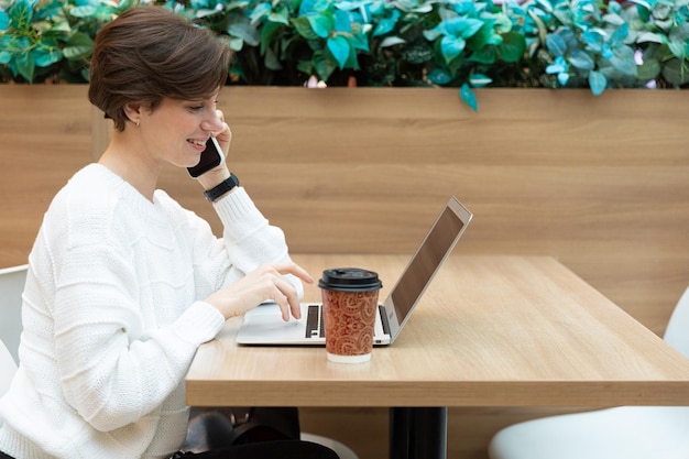 Giovane donna che lavora su un computer portatile e che beve caffè