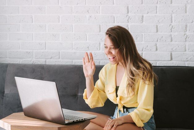 A young woman working on a laptop from home and chatting on a webcam Freelance online education