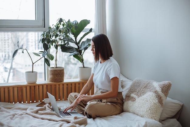 Photo young woman working on laptop at home in bed