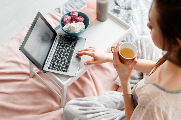 Giovane donna che lavora al computer portatile al mattino.