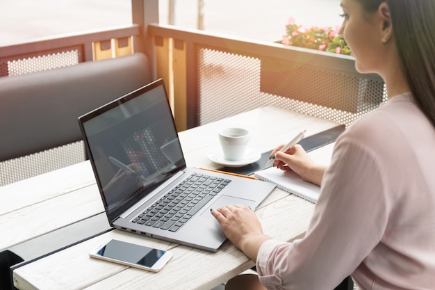 young woman working on laptop and writing