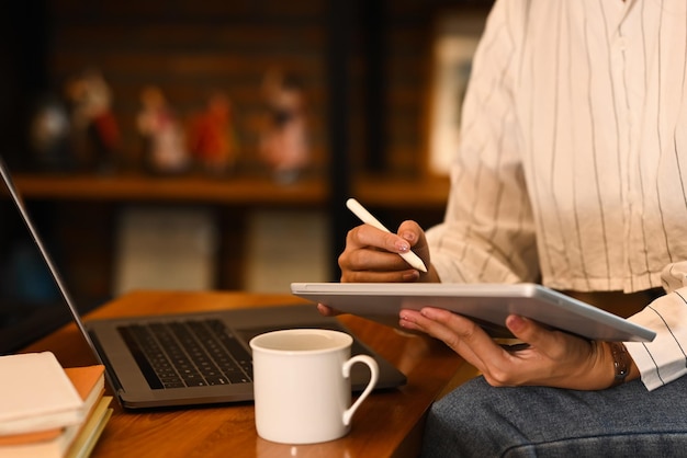 Giovane donna che lavora online da casa navigando in internet con il computer portatile