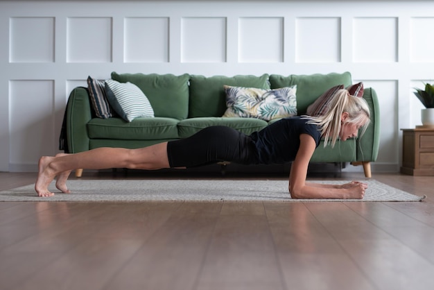 Photo young woman working out at home doing plank exercise