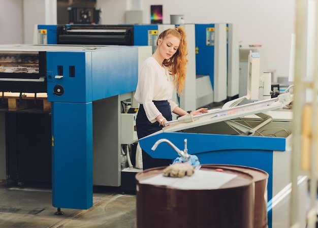 Foto giovane donna che lavora nella fabbrica di stampa macchina da stampa