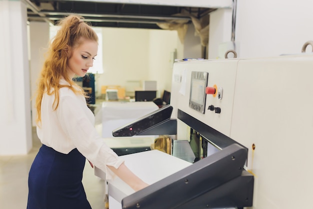 Young woman working in printing factory. Printing Press.