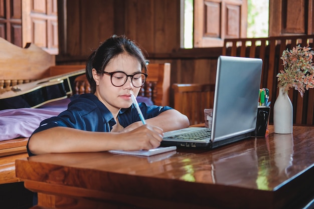 Seduta di lavoro della giovane donna sullo strato con il computer portatile a casa