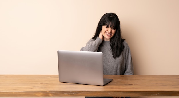 Young woman working with her laptop with neckache