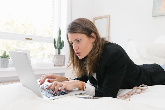 Young woman working with laptop on bed