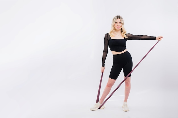 Young woman workout with resistance band on white background strength and motivation