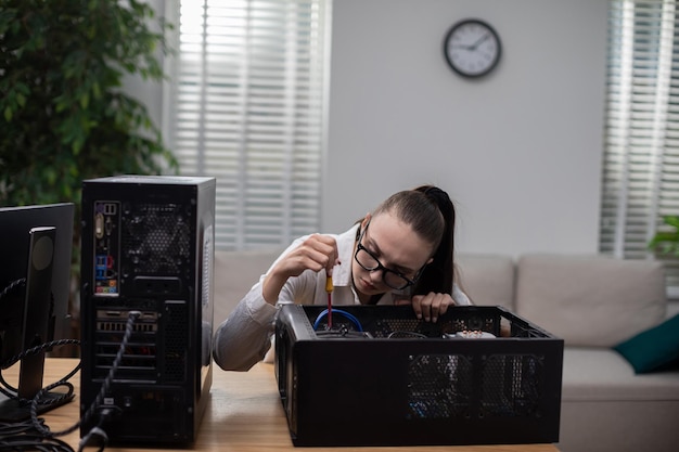 Young woman works as an IT specialist and repairs computer