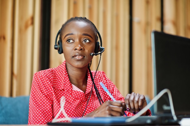 Young woman works in a call center operator and customer service agent wearing microphone headsets working on laptop