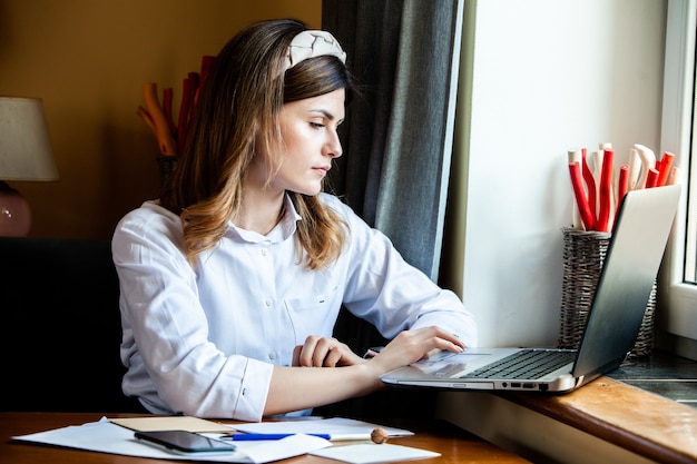 若い女性がカフェでコンピューターで働く