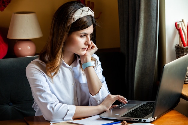 Young woman works at the computer in a cafe