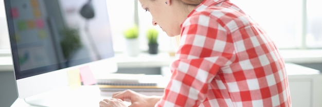 Young woman works at computer with crooked back