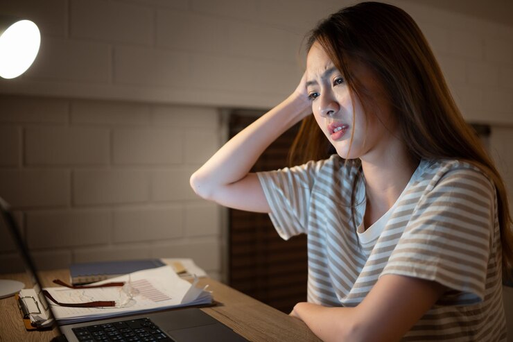 Photo 若い女性が自宅でノートパソコンで作業している. それは頭痛が発生する特徴です.