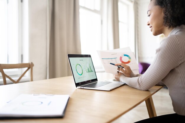 A young woman works in an office uses a laptop checks a report in a finance company