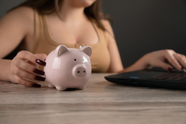 Young woman works with a laptop Piggy bank on the table