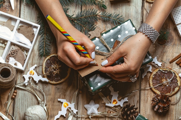 写真 若い女性のラッピングとテーブルにクリスマスプレゼントに署名