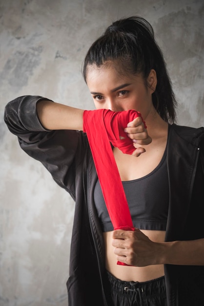 Young woman wrapping bandage while standing indoors